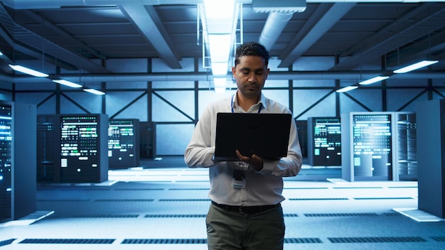 Technician using a laptop to manage servers in a data centre